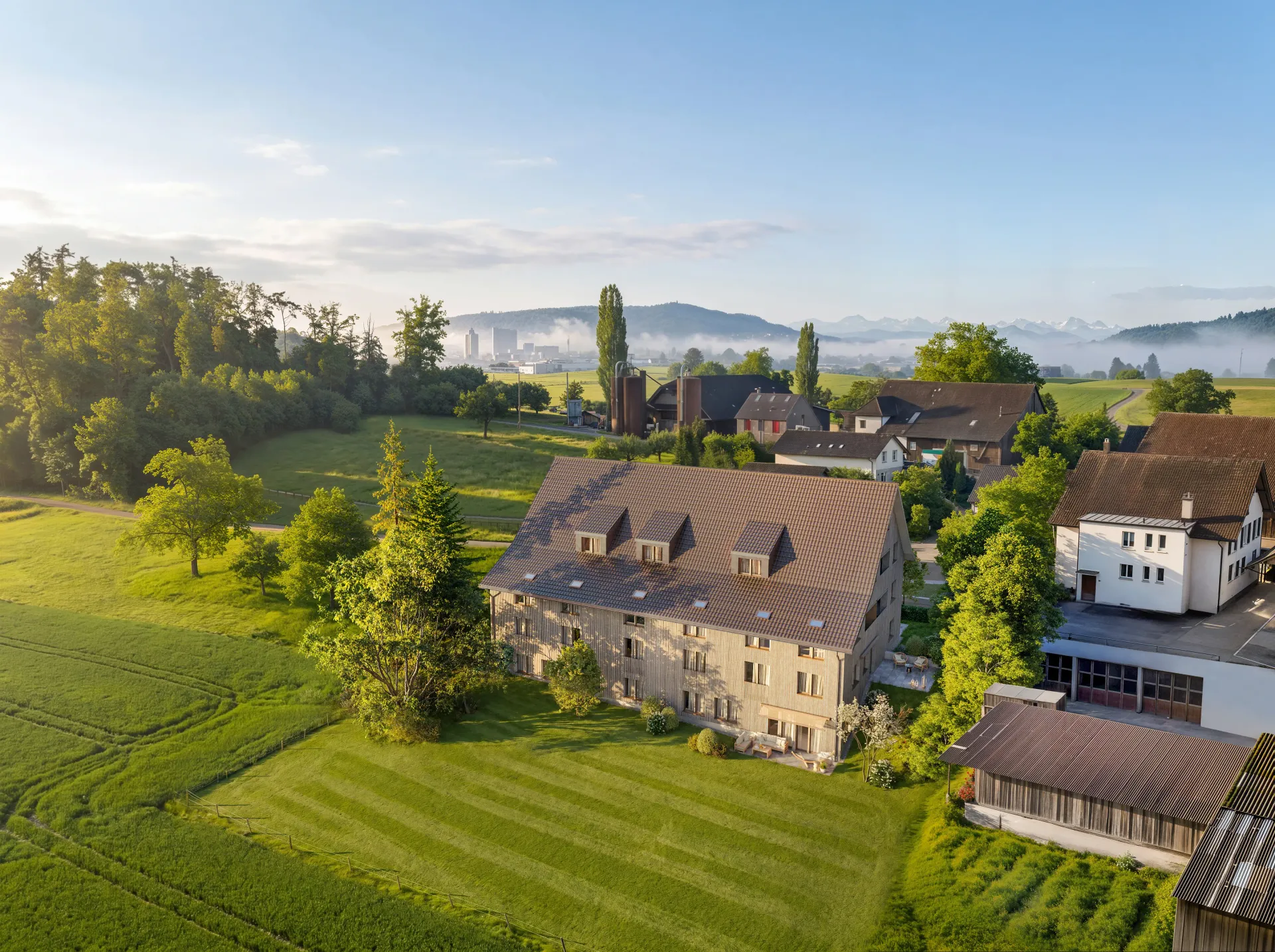 Aerial rendering of a renovated farmhouse with surrounding fields at sunrise