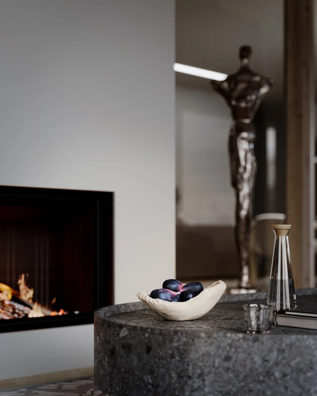 Close-up interior rendering of a fireplace with a decanter and fruit bowl on a stone counter