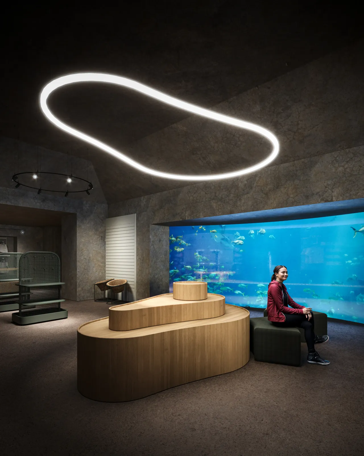 Interior rendering of a dark lounge with a large illuminated ring light and a wall-sized aquarium, a person seated on a curved wooden bench
